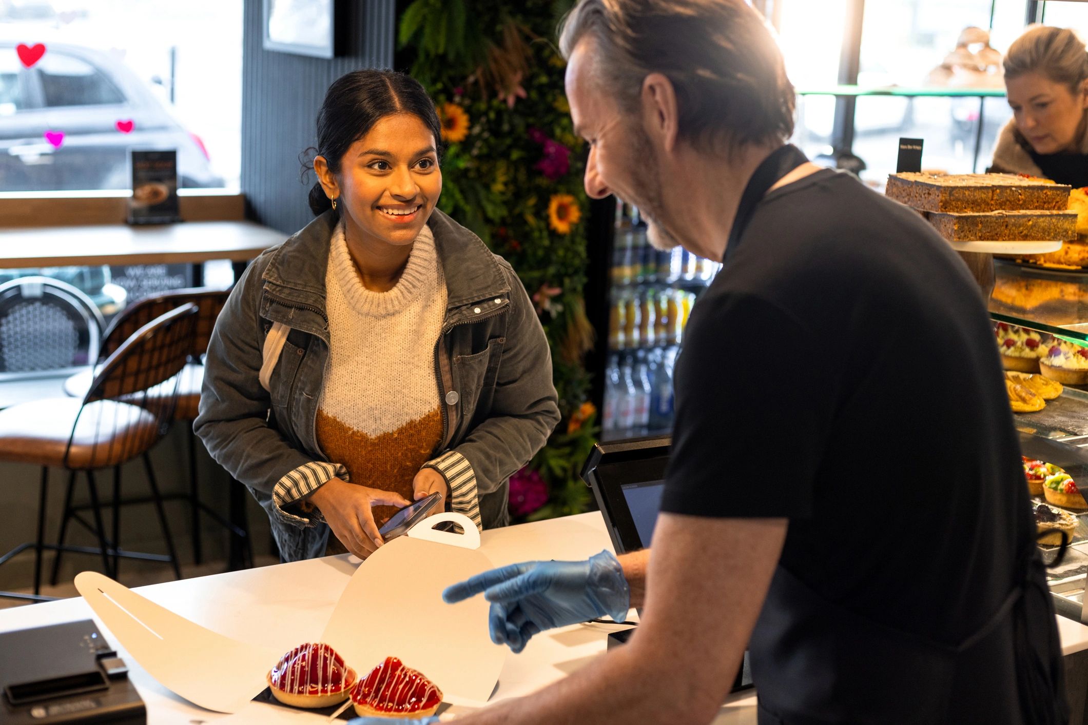 About Customer smiling at a bakery counter while being served